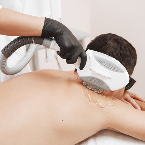 The man came to the procedure of laser hair removal. The doctor treats his neck and face with a special apparatus.