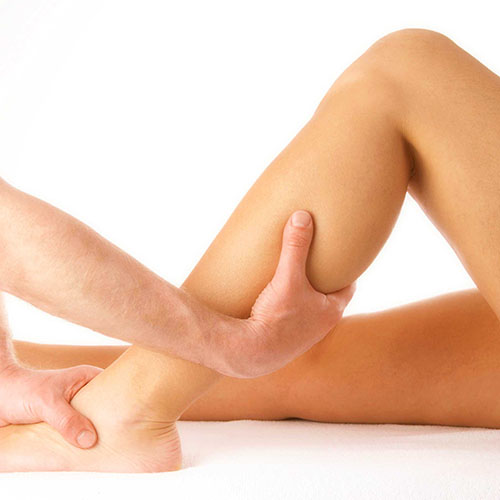 massage of a female calf muscle on white